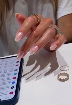 a woman's hands with manicured nails and ring on the table next to her phone