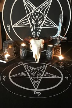 a table with candles and an animal skull on it, surrounded by pentagramus