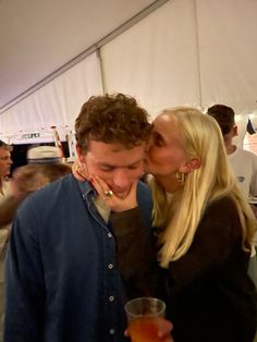 a man and woman kissing while standing next to each other in front of a tent