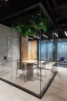 an office with glass walls and plants on the ceiling, along with tables and chairs