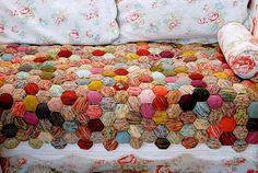 a bed covered with a colorful blanket and pillow on it's headrests