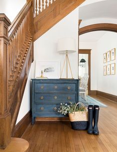 a blue dresser sitting on top of a hard wood floor next to a stair case