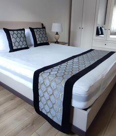 a bed with white sheets and black trim on it's headboard, in a bedroom