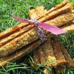 an assortment of crackers tied together in a grass area with a pink ribbon on top