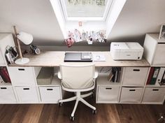 a desk with drawers, printer and other office supplies on it in an attic space