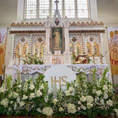 the altar is decorated with white flowers and greenery