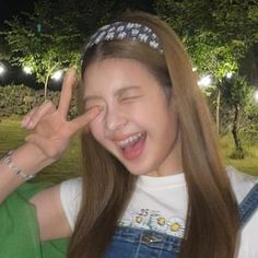 a woman with long brown hair is smiling and making the peace sign in front of her face