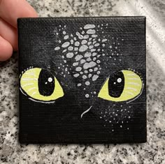 a painting of a black cat's face with yellow eyes on a granite surface