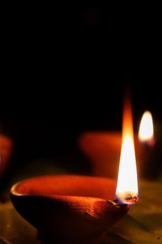 two lit candles sitting on top of a wooden table next to bowls filled with water