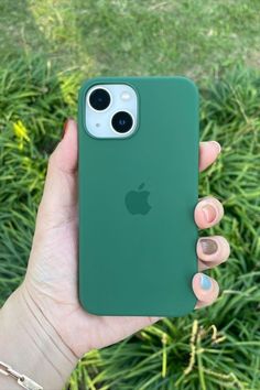 a person holding up an iphone case in front of some green grass and bushes with their fingers