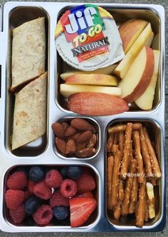 an open lunch box filled with fruit, crackers and sandwiches