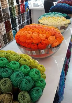 there are many different colors of yarn on the counter in this store, including oranges, yellows, and greens