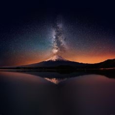 the night sky is filled with stars above a mountain and lake in front of it