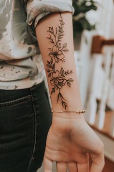 a woman's arm with a flower tattoo on the left side of her hand