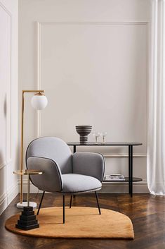 a living room with a chair, table and lamp on the floor in front of it