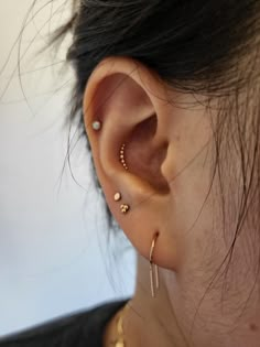 a close up of a person wearing ear piercings and gold rings on their ears