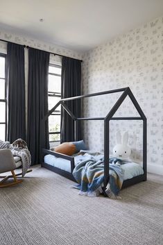 a child's room with a bed, rocking chair and stuffed animal on the floor