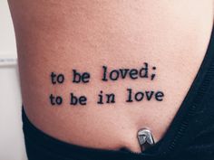 a woman with a tattoo on her stomach that says to be loved, to be in love