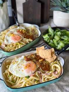 two pans filled with pasta and eggs on top of a table