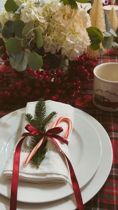 the table is set with white plates and red ribbon