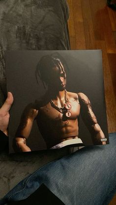 a man with tattoos on his chest is holding up a book in front of him