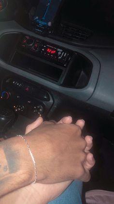 a man driving a car with his hand on the steering wheel while wearing a bracelet