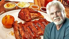 an older man sitting in front of a plate of food with ribs and potatoes on it