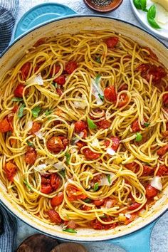 a pan filled with pasta and sauce on top of a blue plate next to wooden spoons