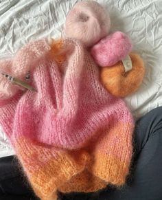 a knitted teddy bear laying on top of a bed next to a ball of yarn