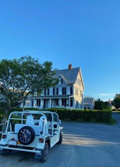 a golf cart parked in front of a large white house on the side of a road