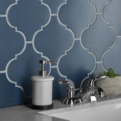 a white sink sitting under a faucet next to a blue tiled bathroom wall