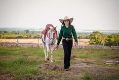 a woman in a cowboy hat walking a horse