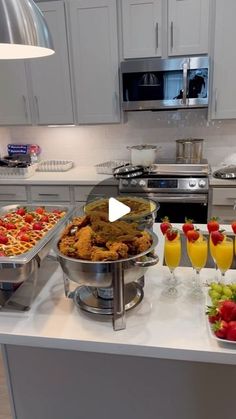 a kitchen counter topped with lots of trays of food and drinks on top of it