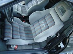 the interior of a car with two seats and one steering wheel in grey, blue and red striped upholster