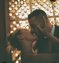 a man and woman kissing each other in front of many lit candles on the wall