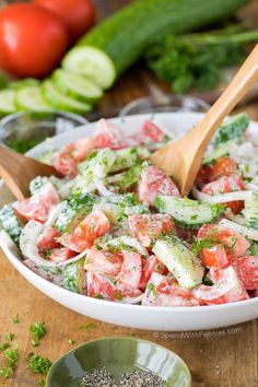 cucumber tomato salad in a bowl with a wooden spoon