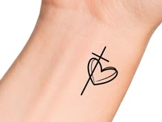 a cross and heart tattoo on the left side of the wrist is shown in black ink