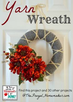 the yarn wreath is hanging on a door with red flowers and greenery in it