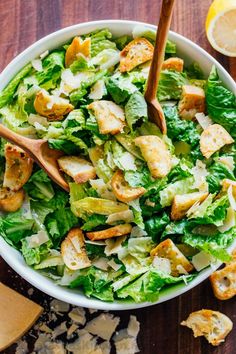 a salad with lettuce, chicken and croutons in a white bowl