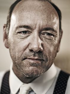 a black and white photo of a man with wrinkles on his face, looking at the camera