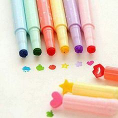 four different colored markers sitting next to each other on top of a white surface with hearts and stars