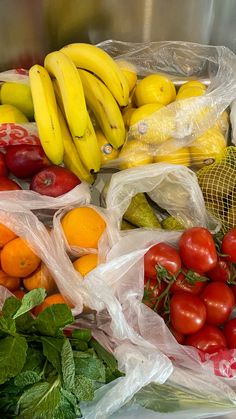 many different types of fruits and vegetables in plastic bags