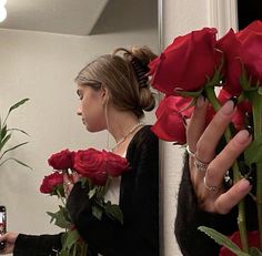 a woman taking a selfie in front of a mirror with roses