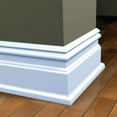 the corner of a room with wood flooring and white trim on it's base