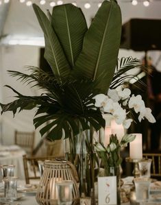 there is a vase with flowers and candles in it on the table at this wedding reception