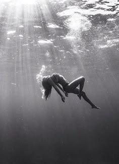 a woman diving in the ocean with sunlight streaming through her face and head above water's surface