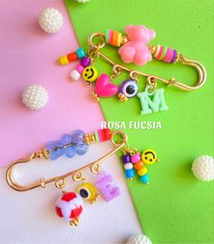 three key chains with charms on them sitting next to each other in front of a green and pink background