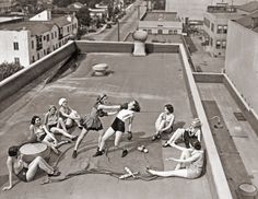 an old black and white photo of women playing with frisbees on a rooftop