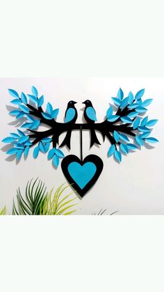 two blue birds sitting on top of a tree branch next to a heart shaped cutout