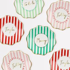 four decorated cookies with the words merry written in gold, green, red and white stripes